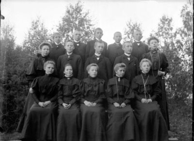 Gruppebilde 1900 - 05  Ytre Enebakk
Konfirmasjonsbilde 7 jenter og 8 gutter. Ute. Svarte kjoler.
Nøkkelord: gruppebilde;konfirmasjon;ytre;gutter;jenter;kjoler;pyntet;dress;smykker