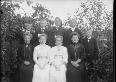 Gruppebilde 1910  Ytre Enebakk
Konfirmasjonsbilde 4 jenter, 5 gutter. Utendørs. To jenter i hvite kjoler, de andre i svart.
Nøkkelord: gruppebilde;konfirmasjon;ytre;gutter;jenter;kjoler;smykker;trær;utendørs;hvitkjole