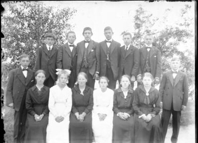 Gruppebilde 1905 -10  Ytre Enebakk
Konfirmasjonsbilde 6 jenter, 8 gutter. 2 i hvite kjoler, utendørs.
Keywords: gruppebilde;konfirmasjon;ytre;gutter;jenter;kjoler;dress;pyntet;utendørs;smykker;tre;trær