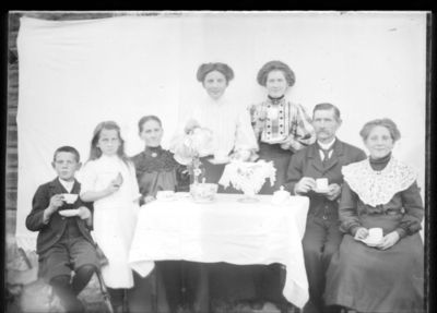 Gruppebilde 1900 -15 
Mann, kvinne og fire piker og en gutt rundt kaffebord. Sannsynligvis familie. Oppstilt bilde.
Nøkkelord: gruppebilde;menn;kvinner;barn;kaffebord;familie
