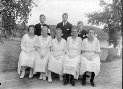 Gruppebilde 1915 -20  Ytre Enebakk
Konfirmasjonsbilde 5 jenter, 3 gutter. Utendørs, vår. Hvite kjoler. 
Nøkkelord: gruppebilde;konfirmasjon;ytre;gutter;jenter;kjoler;dress;pyntet;utendørs;træ;smykker;hvite