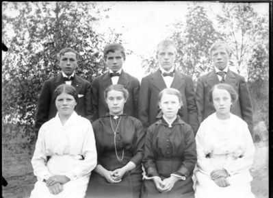 Gruppebilde 1915 -20  Ytre Enebakk
Konfirmasjonsbilde 4 jenter 4 gutter. Utendørs, to i hvite kjoler
Nøkkelord: gruppebilde;konfirmasjon;ytre;gutter;jenter;kjoler;dress;pyntet;utendørs;smykker;tre;trær